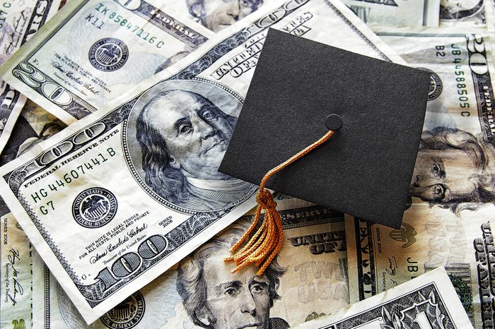 Miniature graduation cap on hundred dollar bills