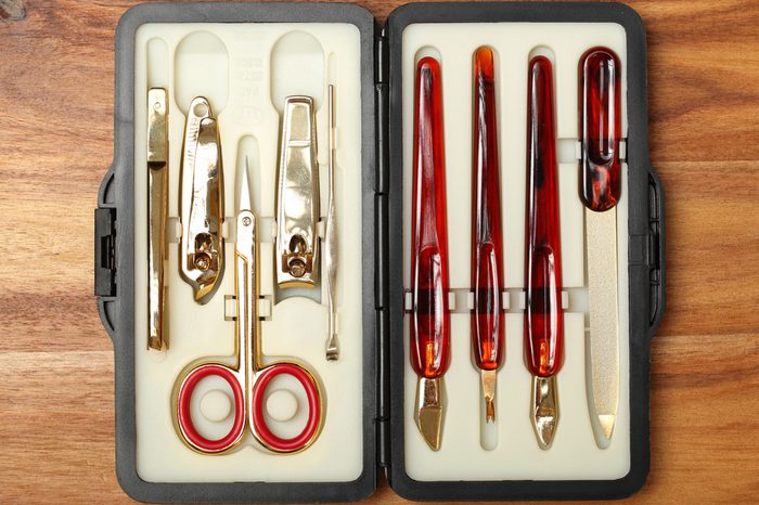 Personal hygiene items on wood background. Metal tweezers, hair clip, nail clippers, and scissors