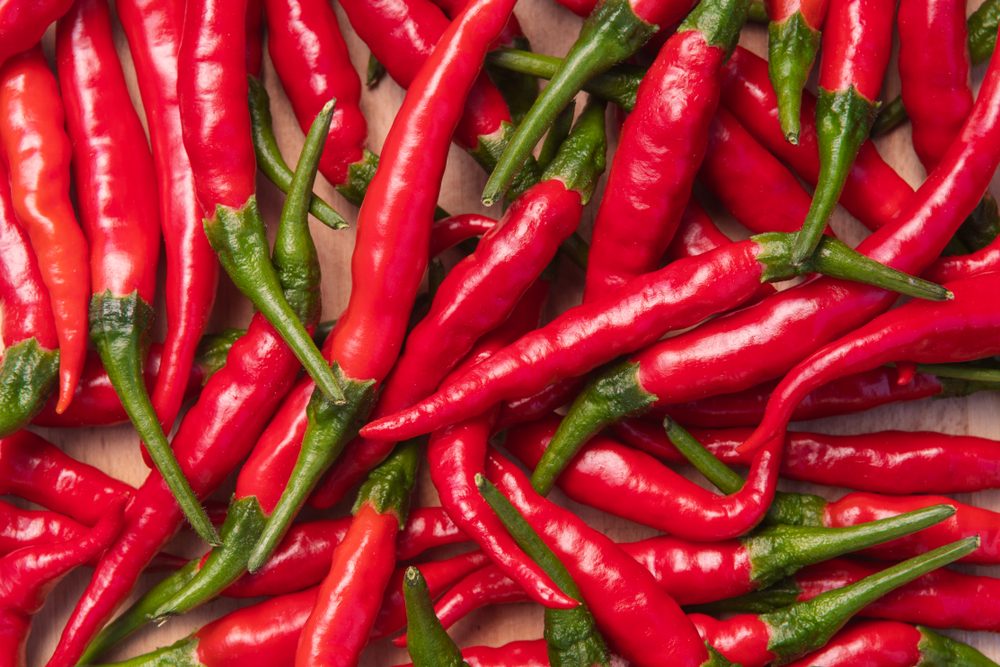 Fresh red hot thai chili peppers on wooden surface