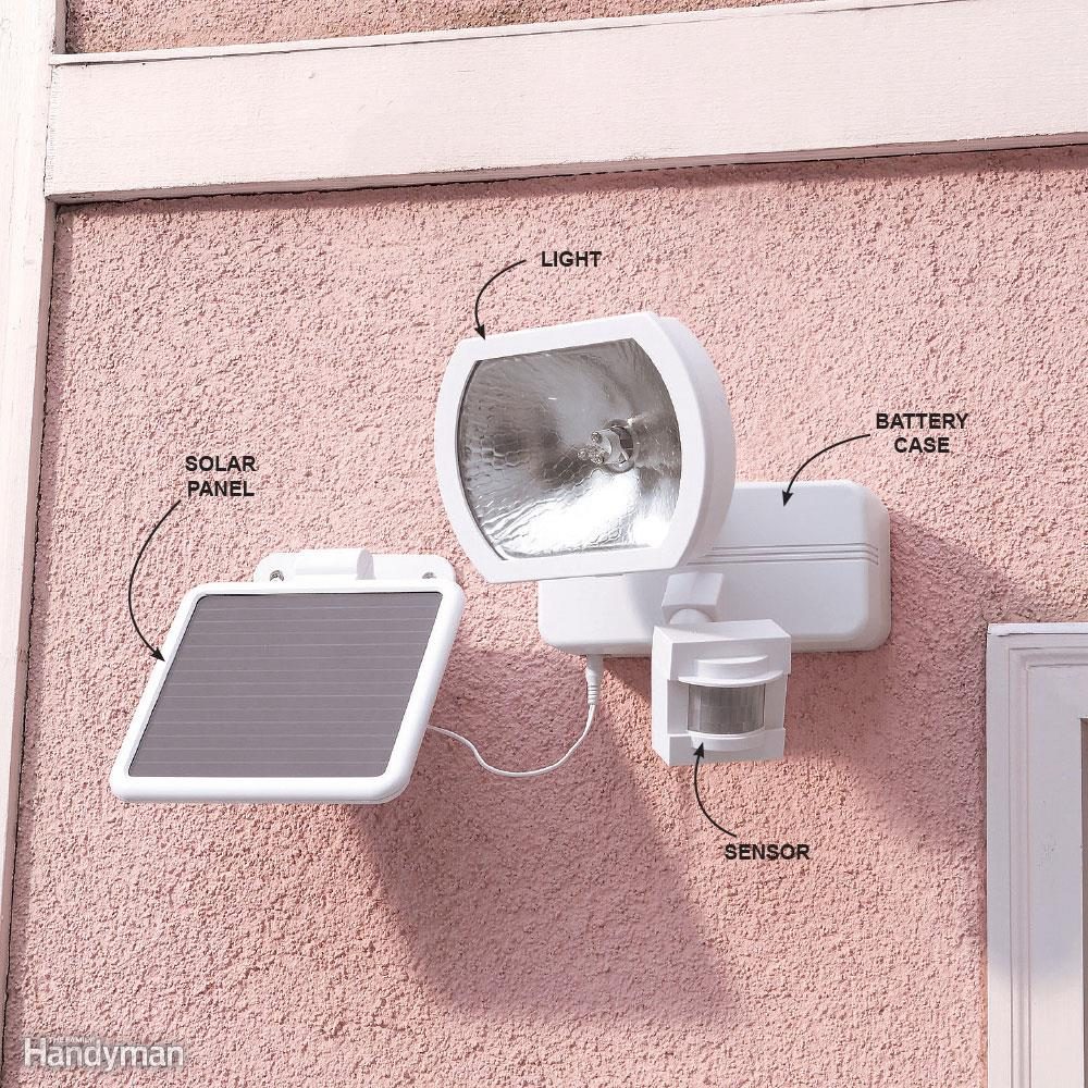 A solar-powered light system with a sensor and battery case is mounted on a pink stucco wall. Labels indicate components: solar panel, light, battery case.