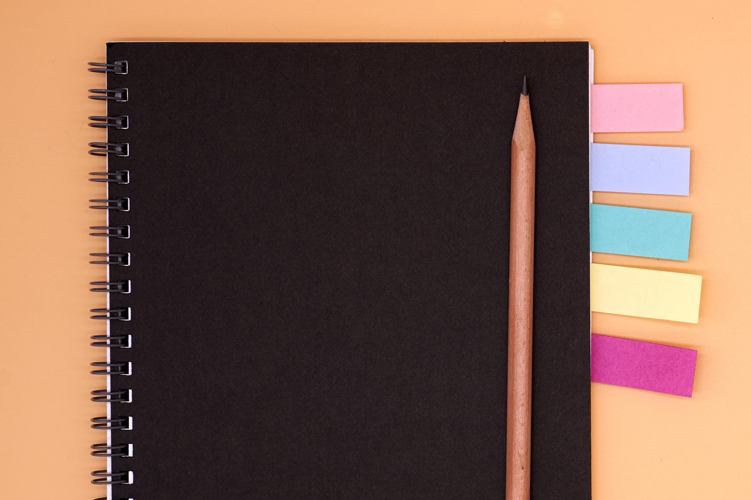notebook with colored flags and pencil