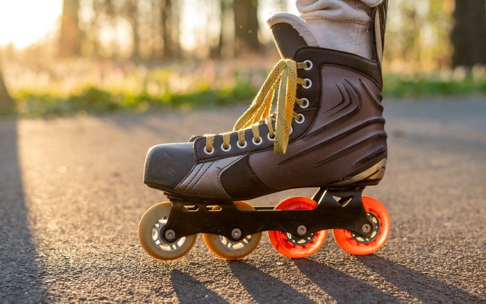 Close view of inline skates. Outdoor inline skating on smooth concrete ground. Ice skating at sunset. Background with bokeh
