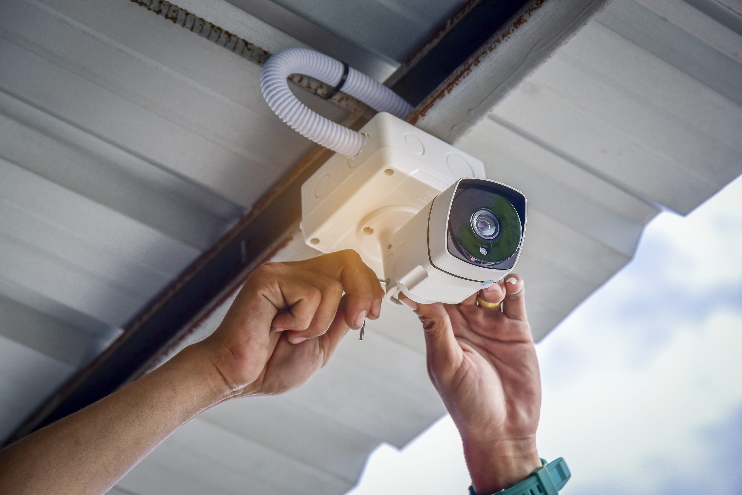 Technician installing CCTV camera by screwed for home security system and car park installed white plastic boxes for safe from water and rain