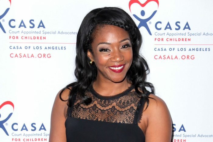 Woman smiling, wearing a black lace dress, stands against a backdrop reading "CASA Court Appointed Special Advocates for Children," including CASA logo and CASALA.ORG.