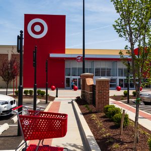 Shopping cart sits in an empty parking lot; red building with Target logo and entrance visible in the background.