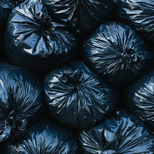 Black garbage bags are tightly packed together, creating a uniform texture across the frame.