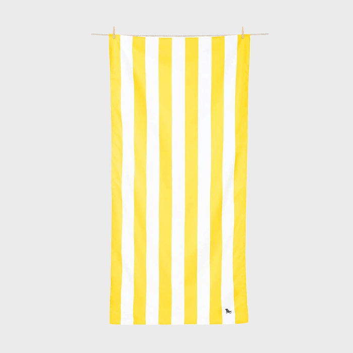 Rectangular towel hangs with yellow and white vertical stripes; suspended on a clothesline against a plain gray background.