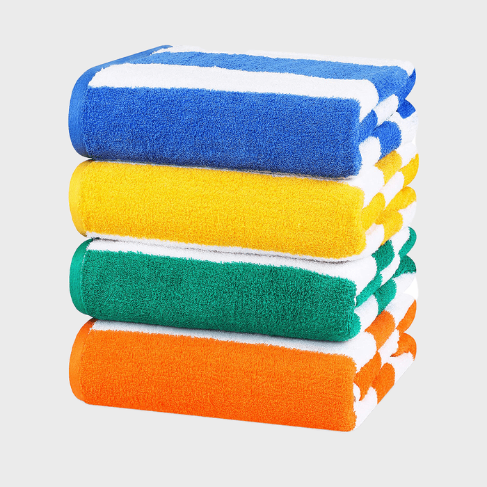 Four folded towels stacked, colored blue, yellow, green, and orange, set against a plain light background.