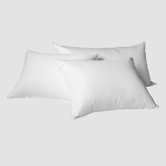 Three fluffy white pillows are stacked against each other on a plain gray background.