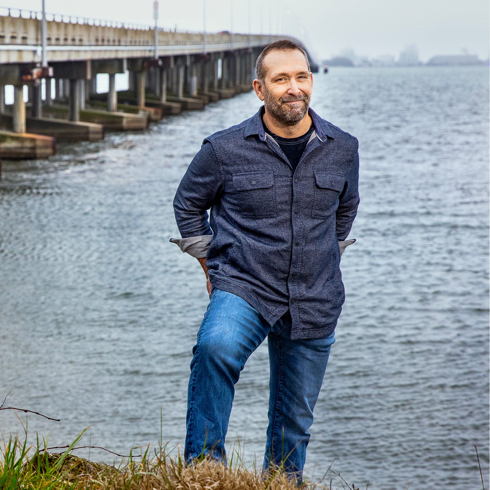 Man standing on the side of a bridge near water