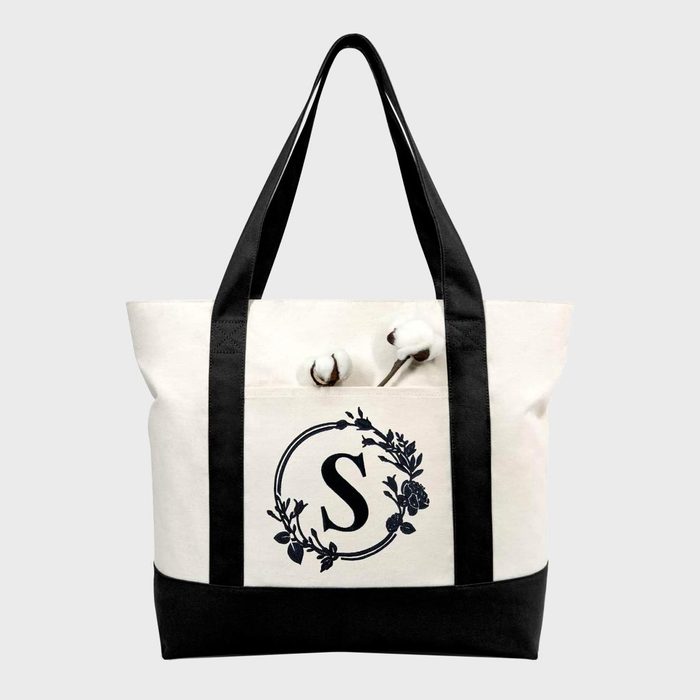 Tote bag displaying black handles and base, decorated with a floral 