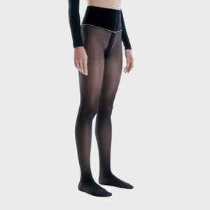 A person is wearing sheer black tights and a high-waisted black band, standing against a plain light background.