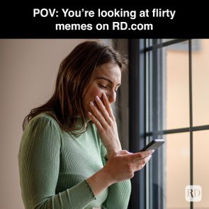 Woman smiling, holding a phone indoors, near a window. Text reads: 