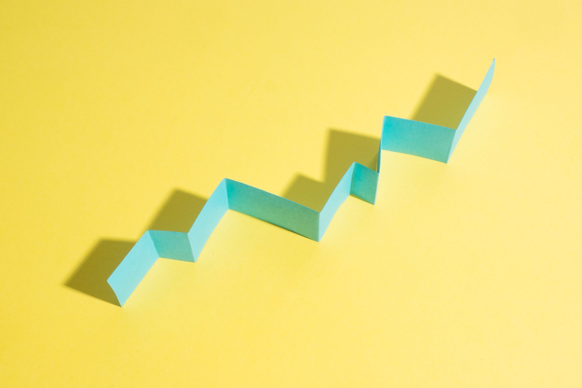 Blue zigzag paper casts shadow on a bright yellow background.