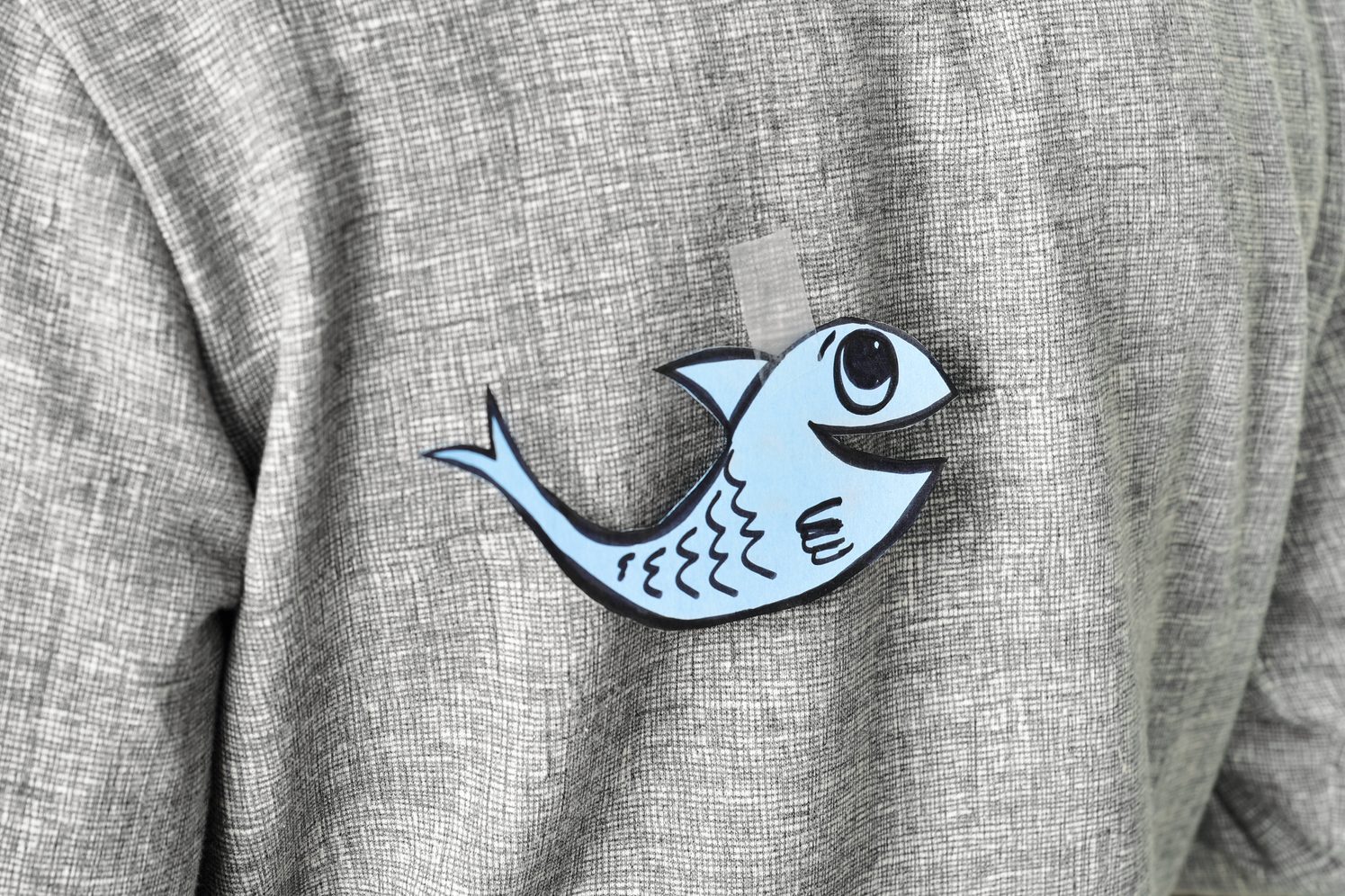 young man with a paper fish attached to his back