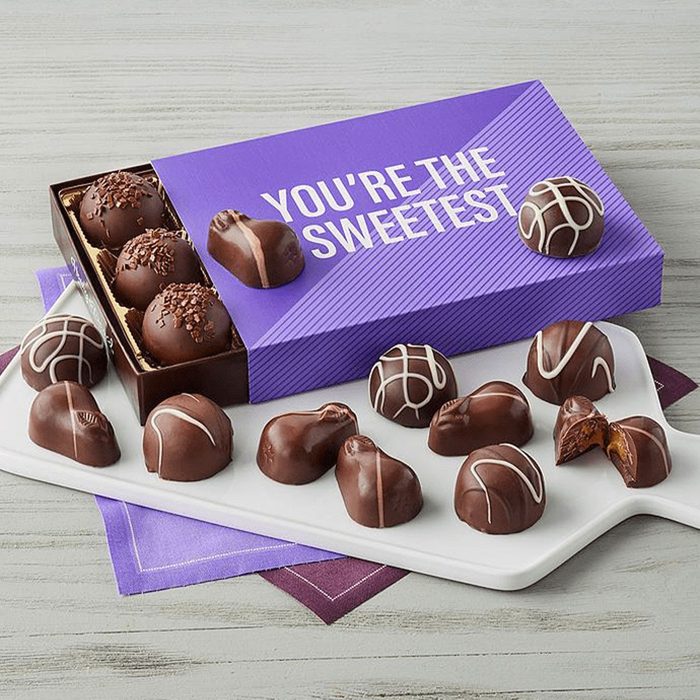 Chocolates rest on a cutting board and partially open purple box with 