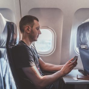 Man using a smartphone while sitting in an airplane seat