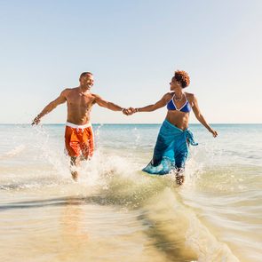 Couple running through shallow waves at a warm beach