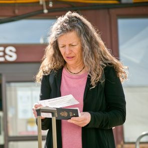 A woman looks at her paper boarding passes with her U.S. passport in front of a departure door