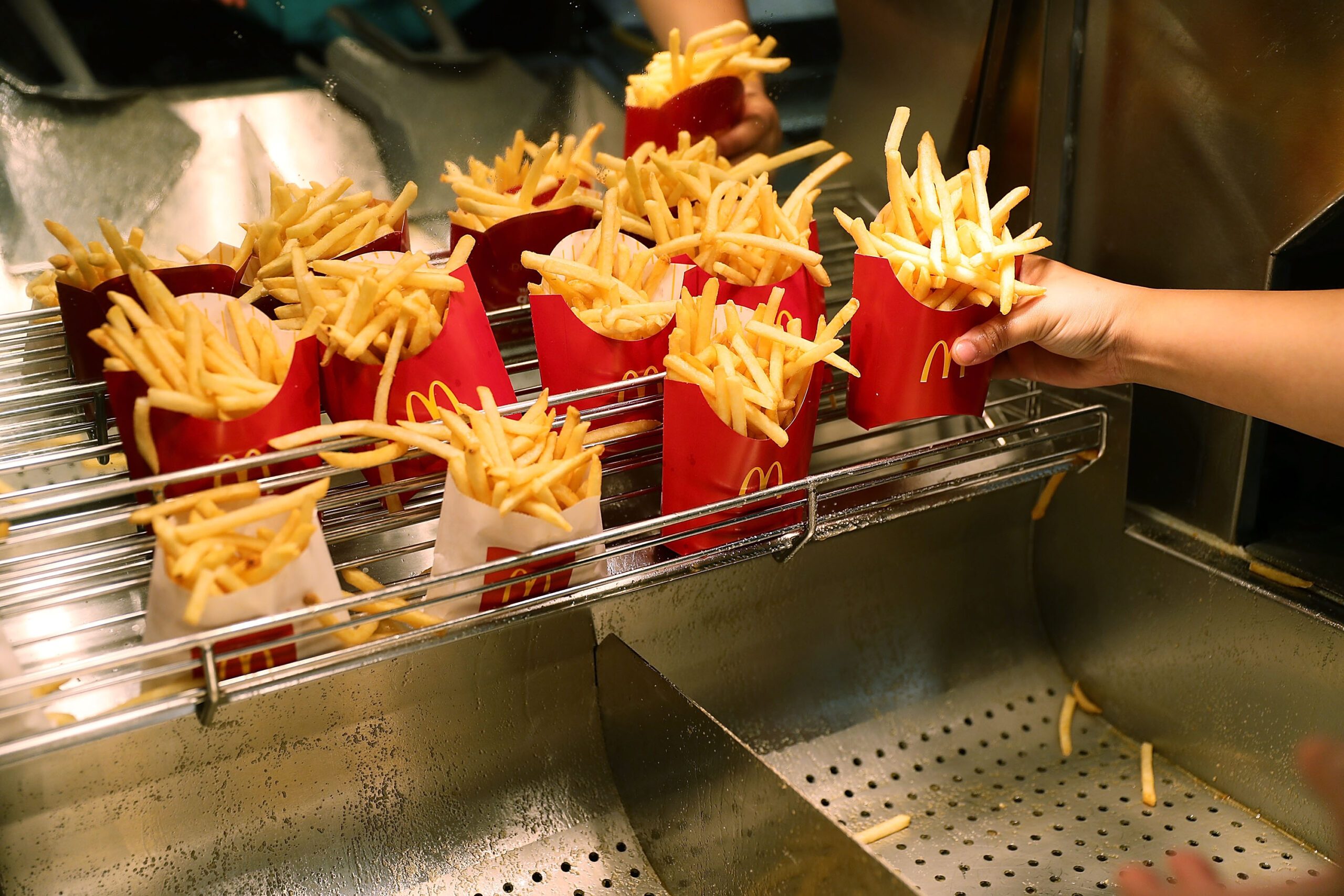 Hand grabbing carton of McDonald's french fries from a warmer