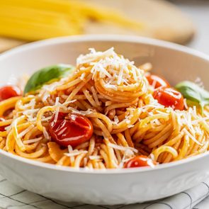 Plate with spaghetti in tomato sauce, parmesan cheese and basil.