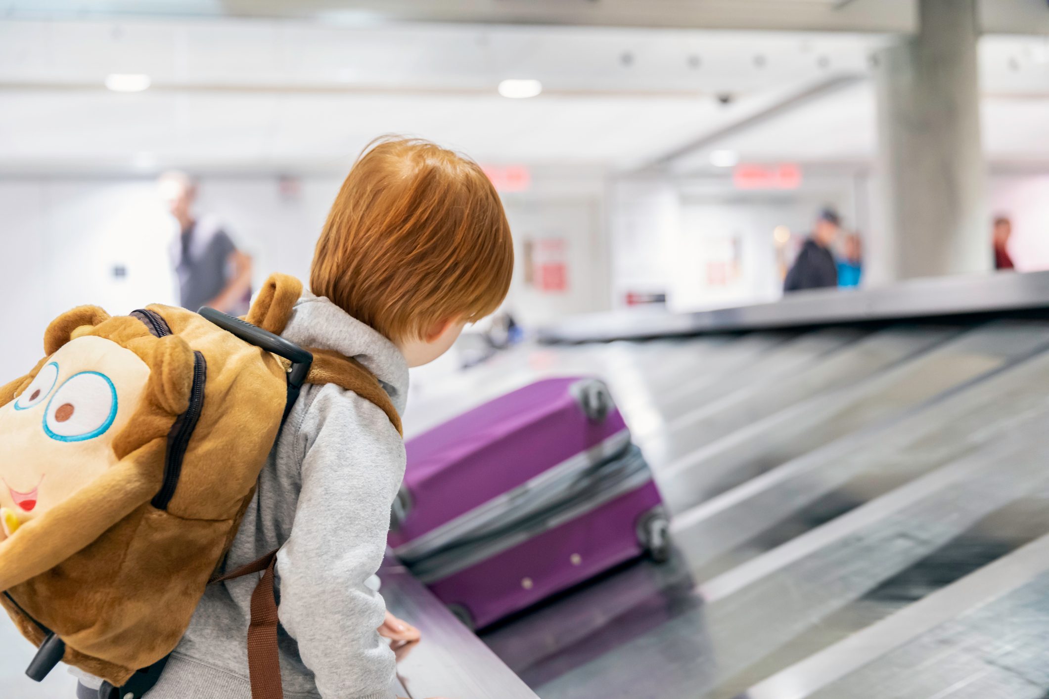 Child Traveler Waiting for Suitcase on Conveyor Belt in Airport