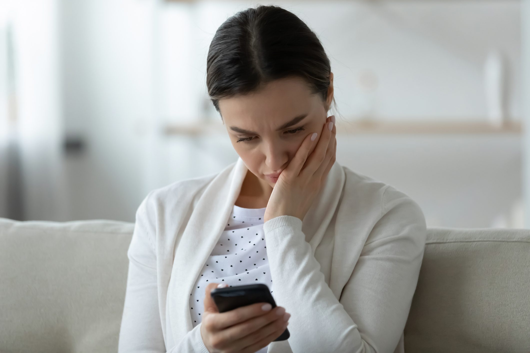 Unhappy young woman having problems with smartphone notifications