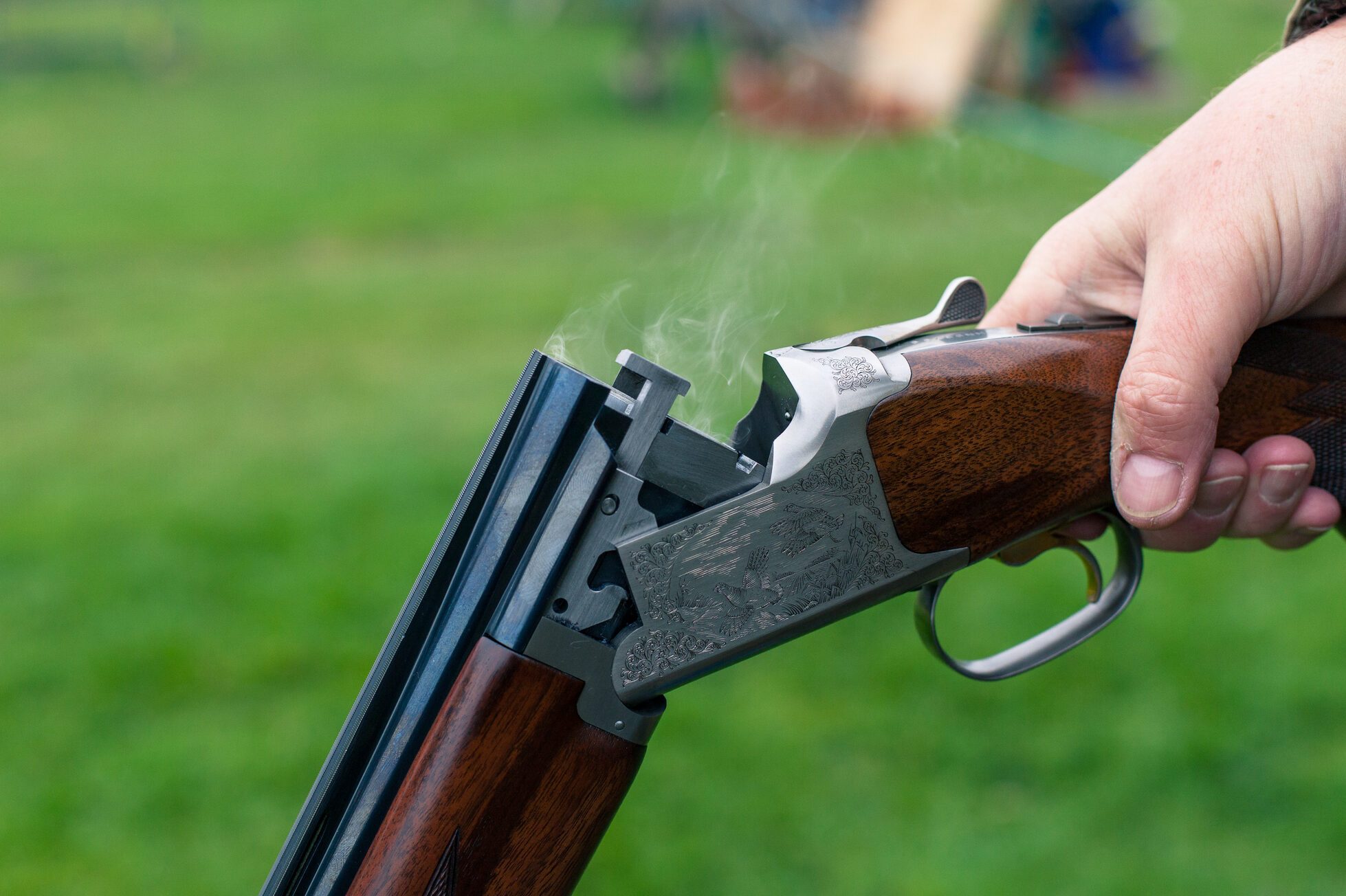 Close up of person holding a shotgun with smoke