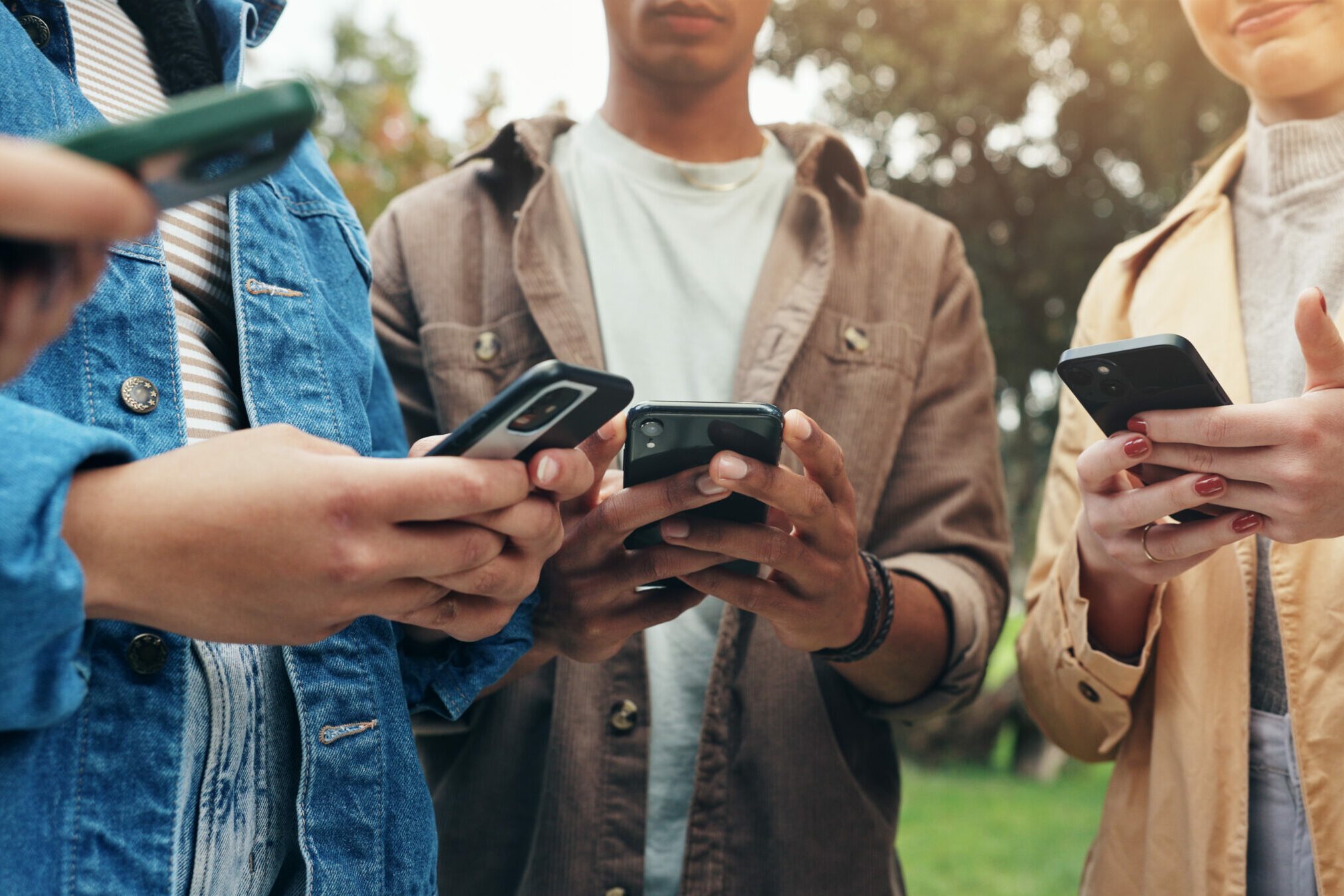 Students, hands and phone outdoor with social media, text and scroll for meme in group on campus. University, garden and college ground with mobile app, streaming and online course with friends