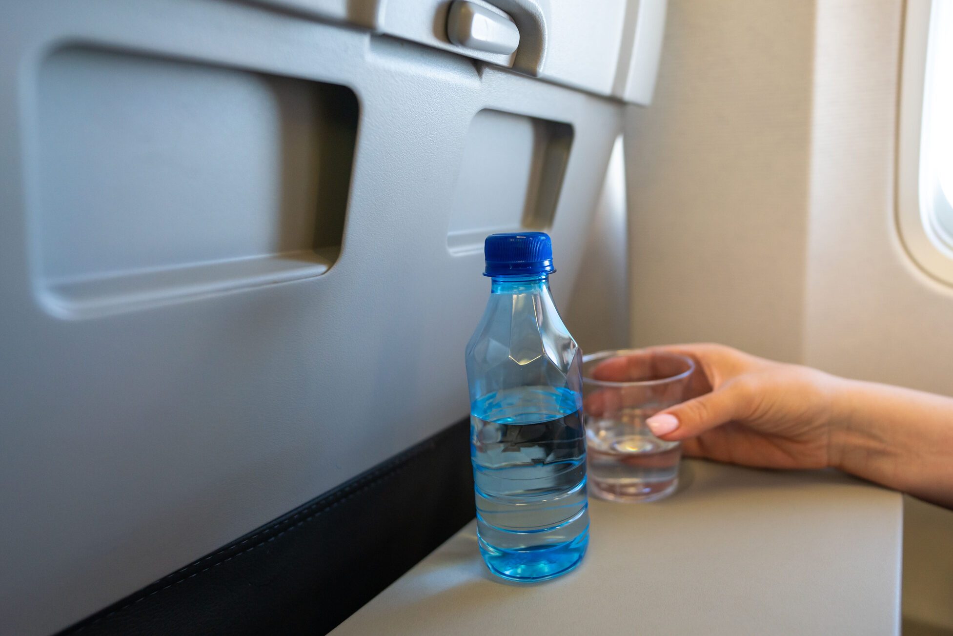 Woman holding plastic glass of water on the aircraft for drinking during the flight
