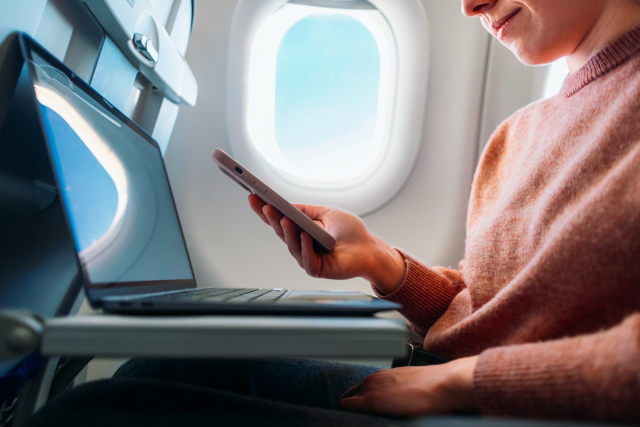 Business Traveler Using Smartphone and Laptop on Airplane Flight