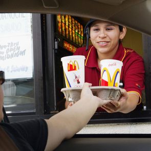 Mcdonald's drive thru worker hands drinks to a customer in his car