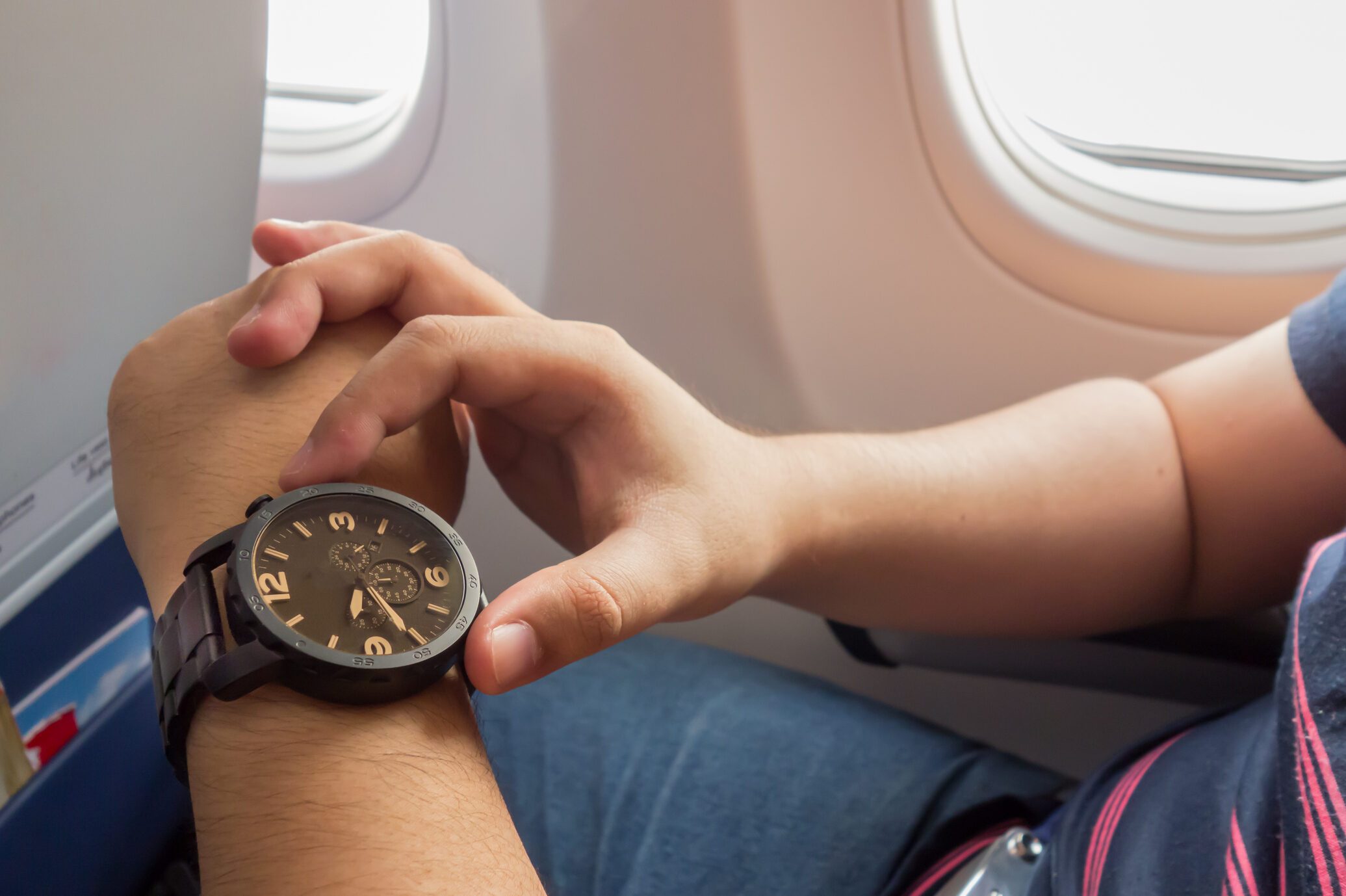 The man looking to the watch on the airplane