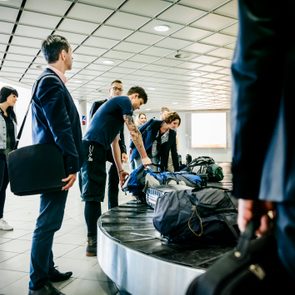 Group of travellers waiting for their luggage at baggage claim