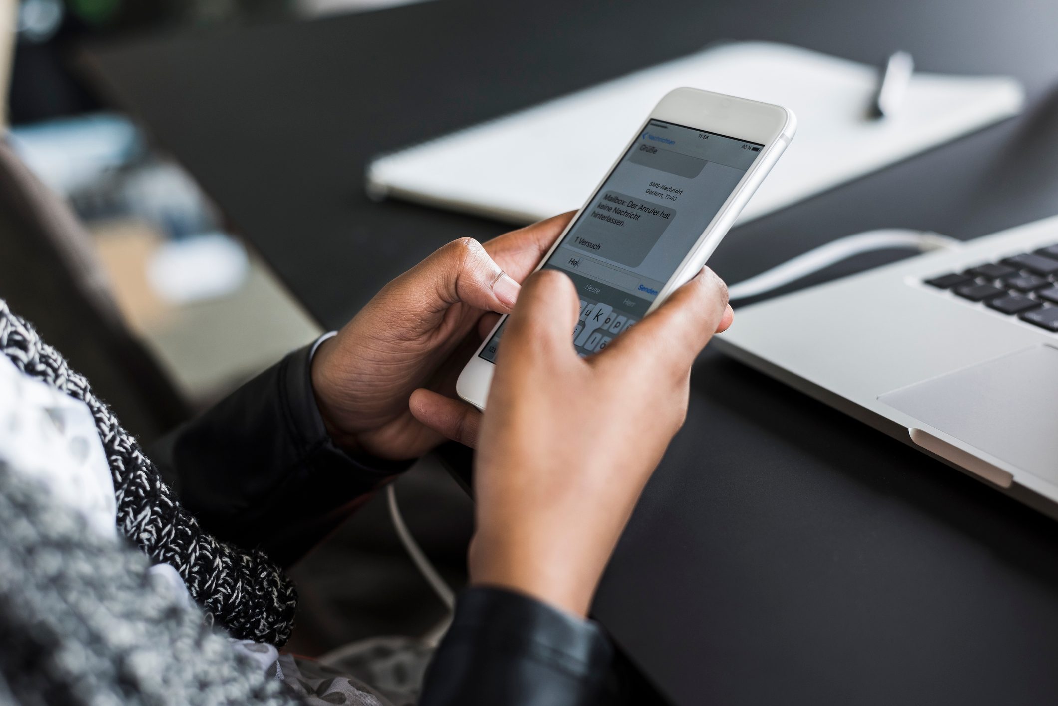 Hands of woman text messaging at desk, close-up