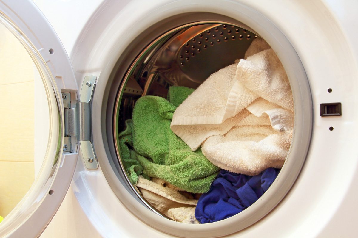 close up of front loading washing machine with clothes inside