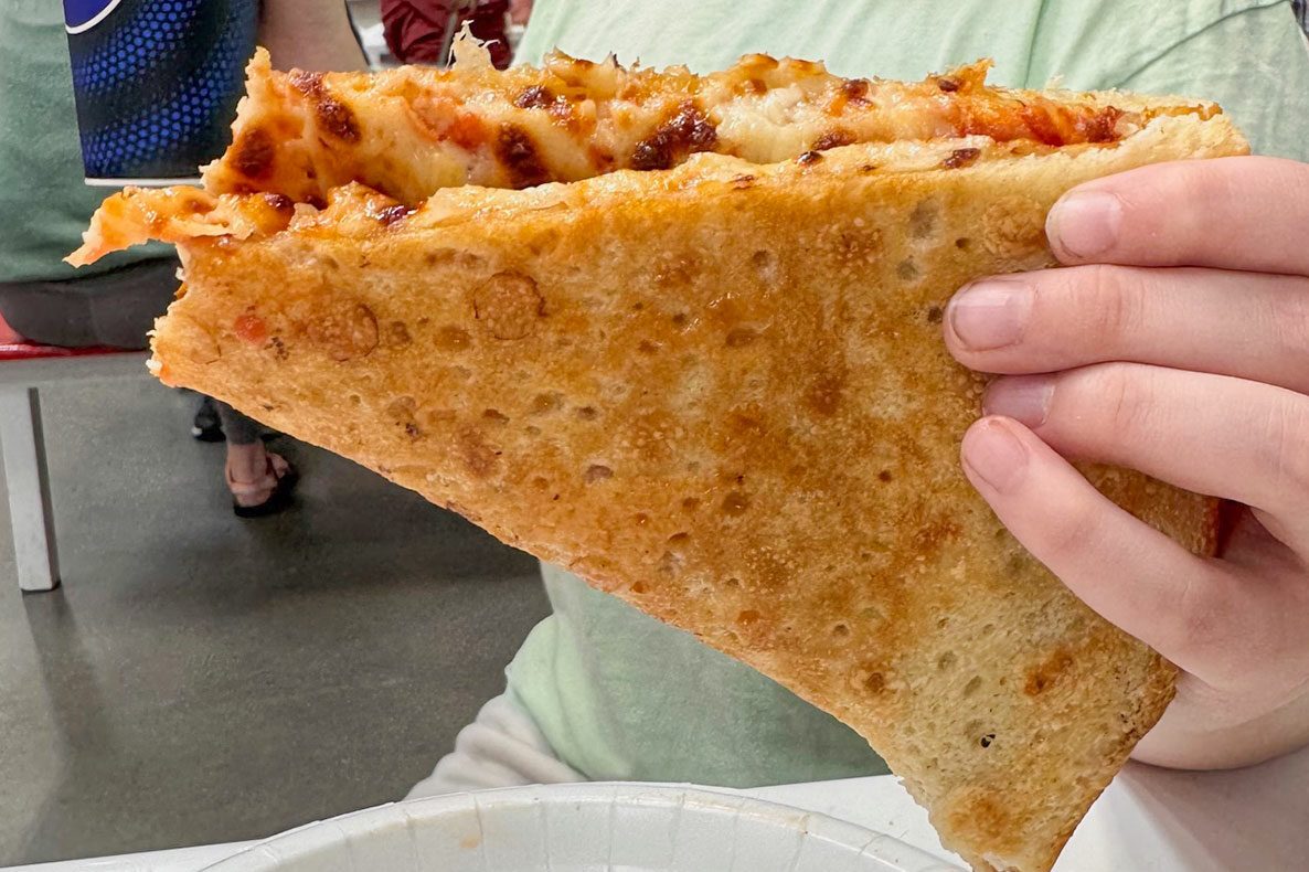 Hand hold a pizza slice in costco