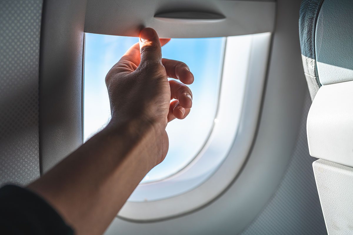 Man Adjusting the Blinds on an Airplane Window