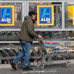 A shopper pushs a shopping cart outside an Aldi store