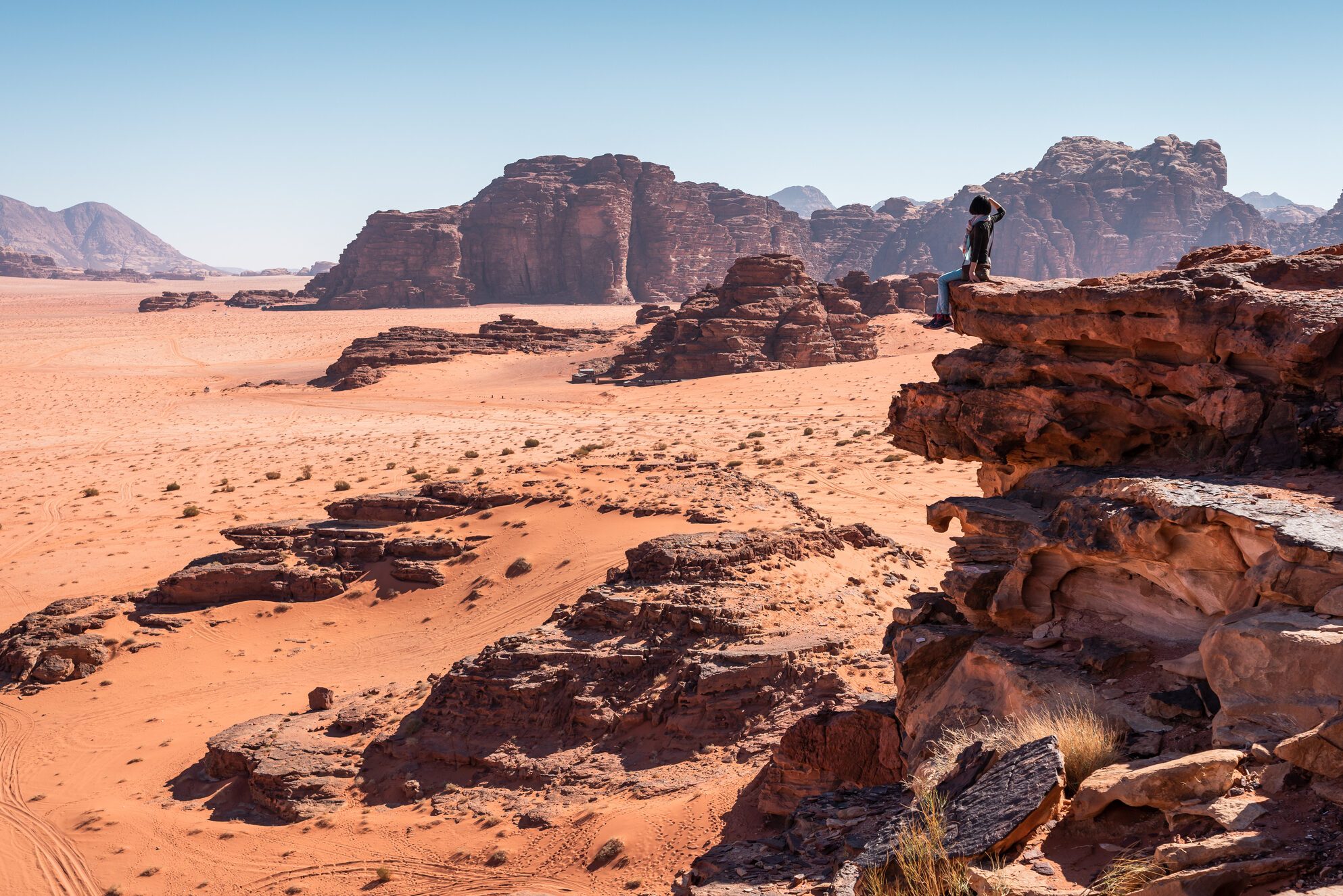 A woman traveller sitting on rock and looking to landscape of Wadi Rum desert in Jordan, Arab
