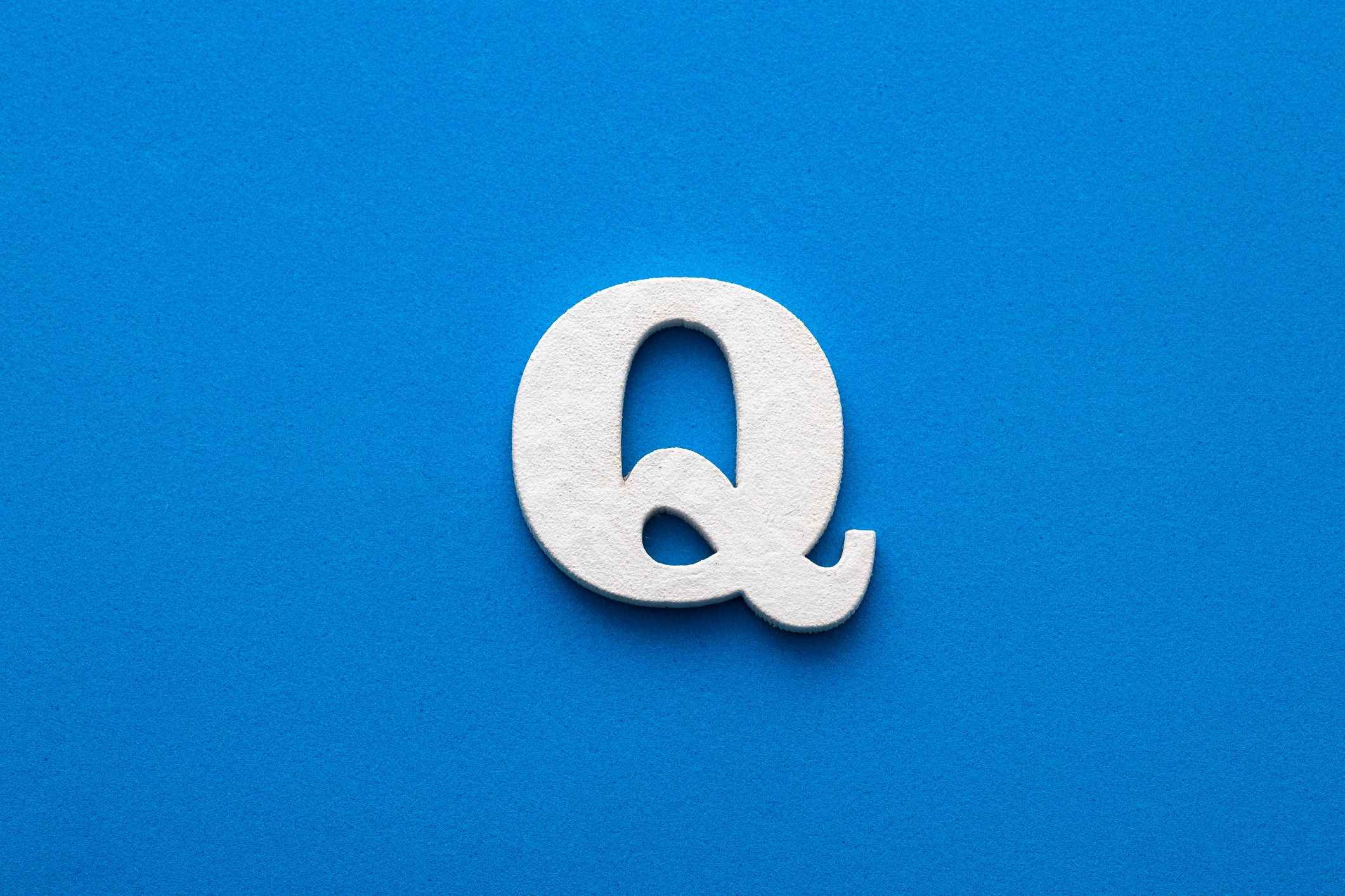 Alphabet letter Q - White wooden letter on blue foamy background