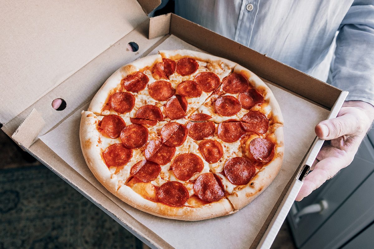 A man holding a pizza box. Close-up.