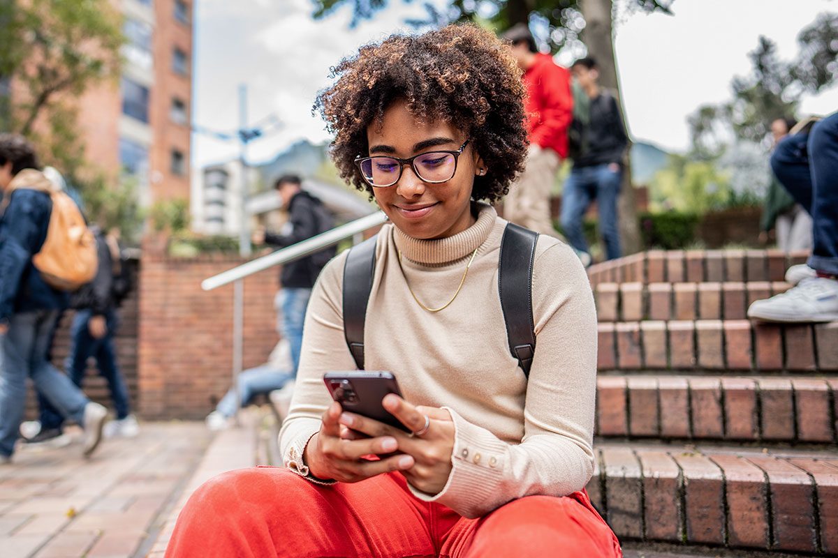 Young university student using mobile phone on stairs outdoors