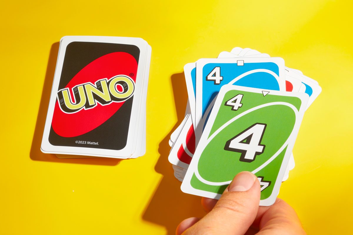 Hand places a card on the discard pile while playing Uno; yellow background