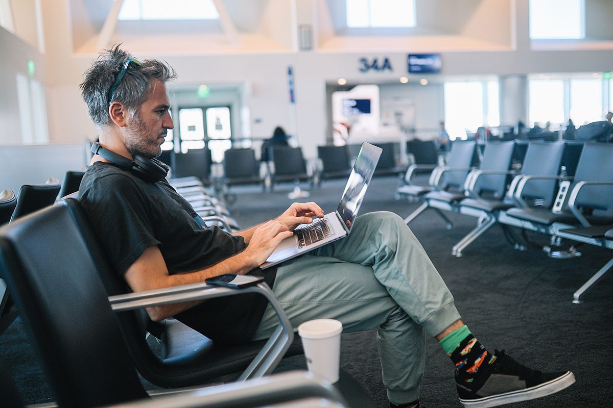 Man working on the laptop while waiting for the flight