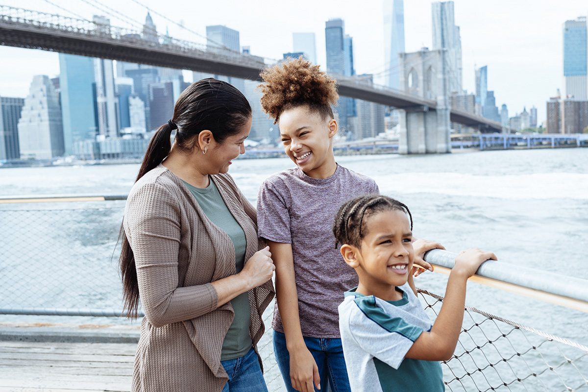 Mother with teenage kids on city break in NYC. Brooklyn bridge and NYC skyline in the background
