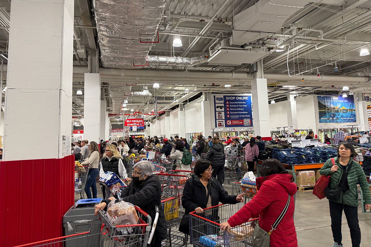 Customers lined up at checkout counters in very busy Costco store